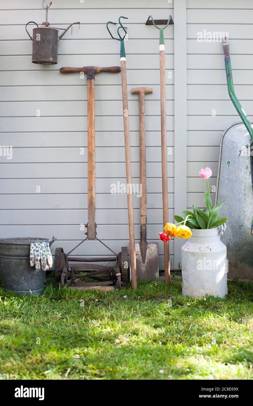 Various gardening tools leaning on shed wall Stock Photo