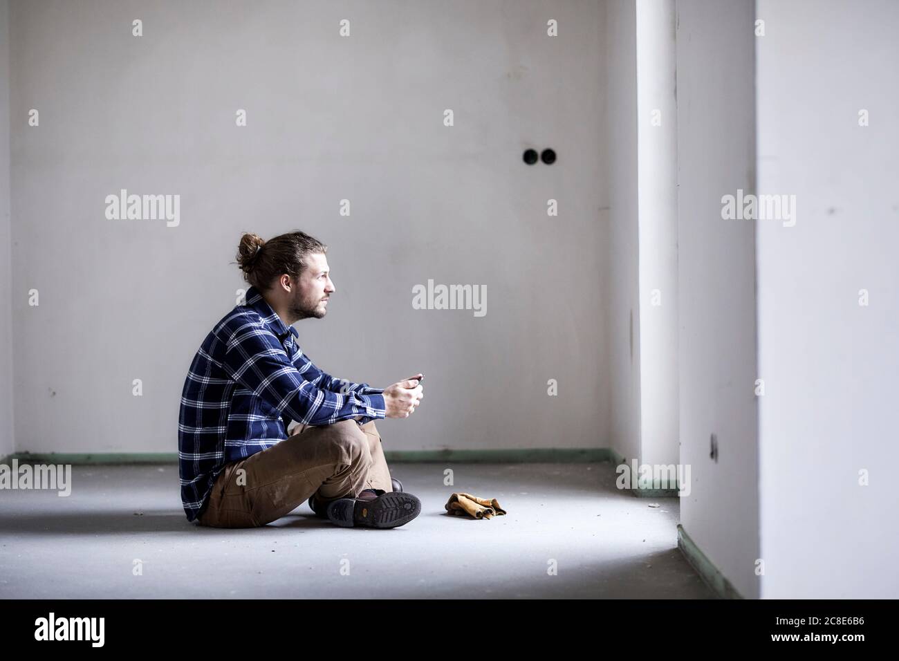 Worker on a construction site sitting on the floor holding tablet Stock Photo