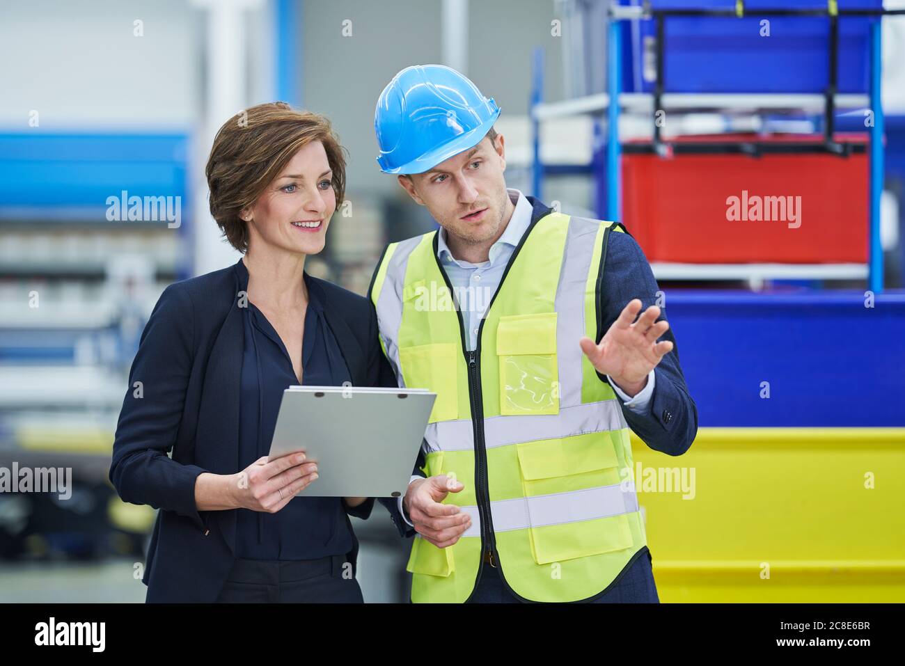 Supervisor explaining plan to female manager holding clipboard in ...