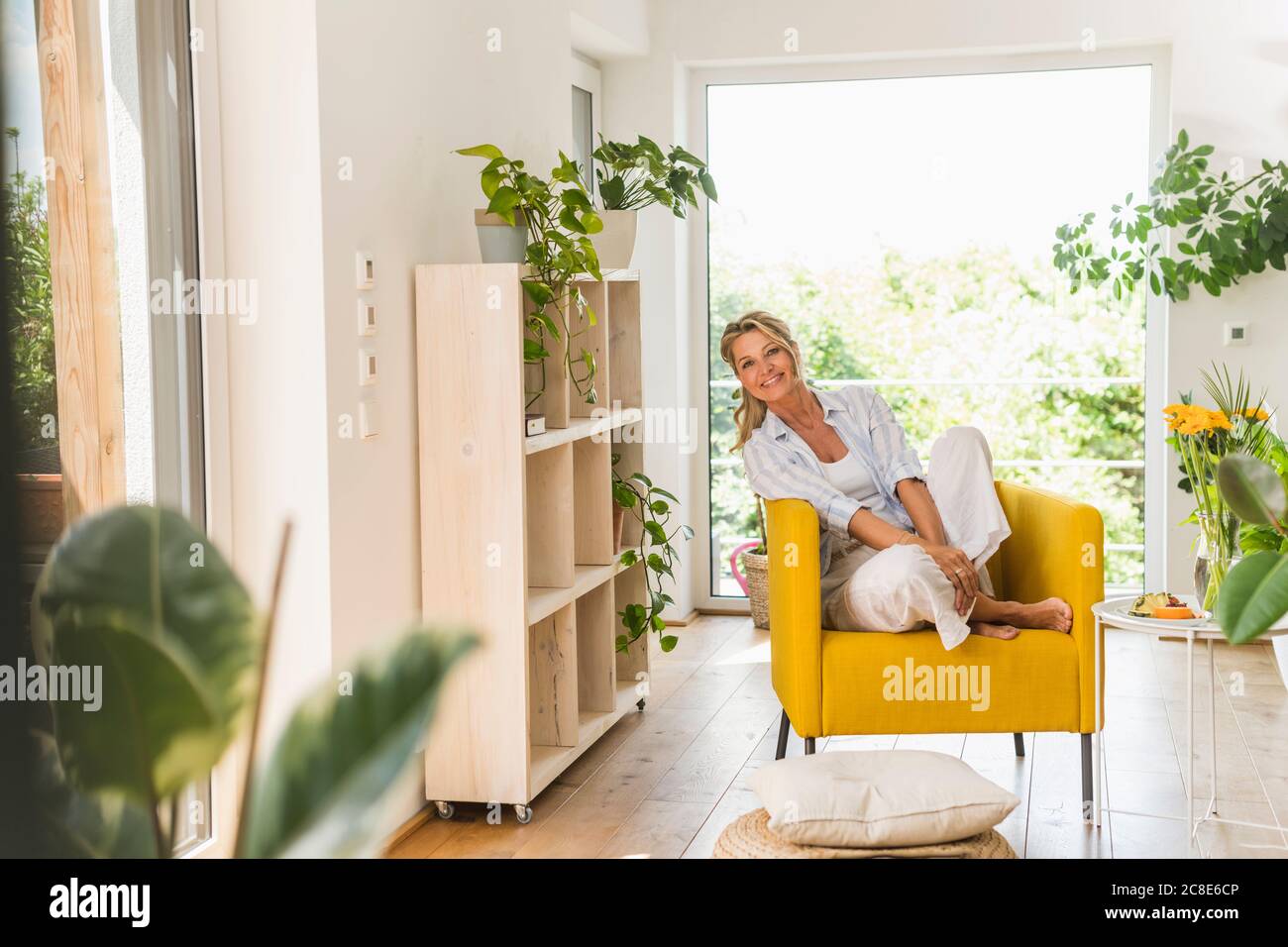 Portrait of smiling mature woman relaxing in armchair at home Stock ...