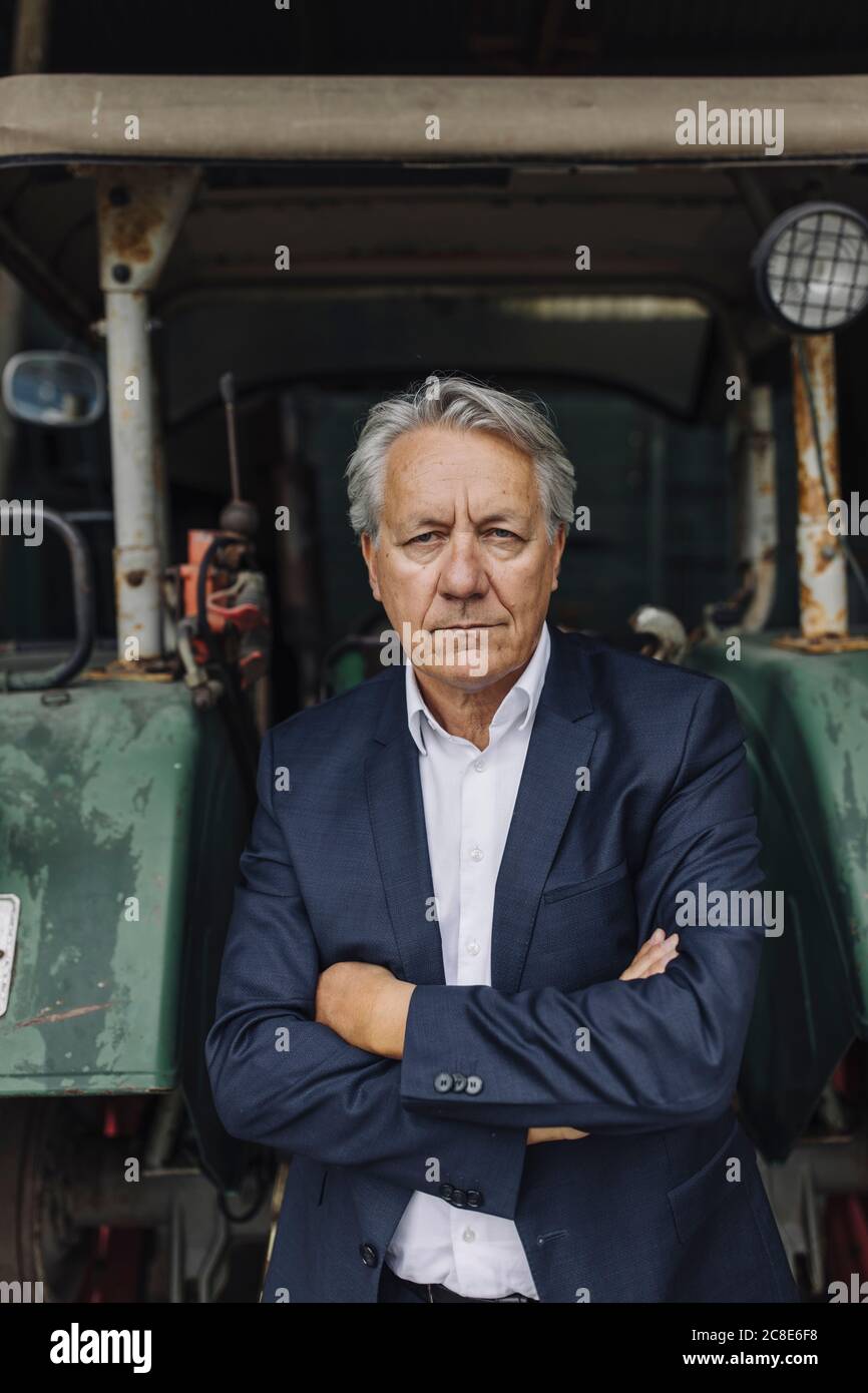 Portrait of a senior businessman at tractor on a farm Stock Photo