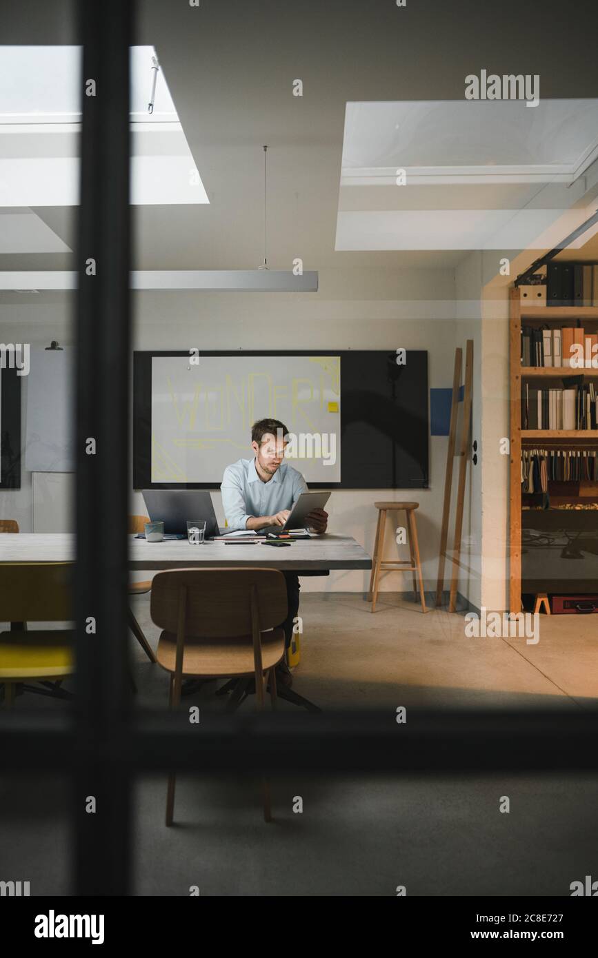 Businessman sitting in loft office, using digital tablet Stock Photo