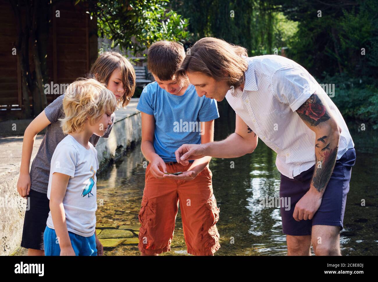 Father and children looking at something found in stream water Stock Photo