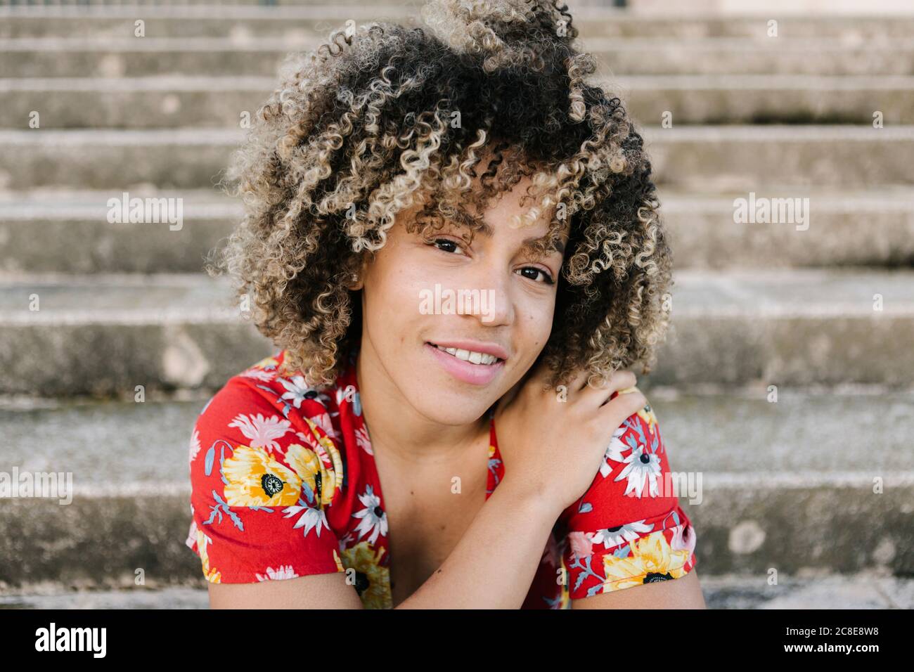 Trendy young woman sitting on steps during sunny day Stock Photo - Alamy