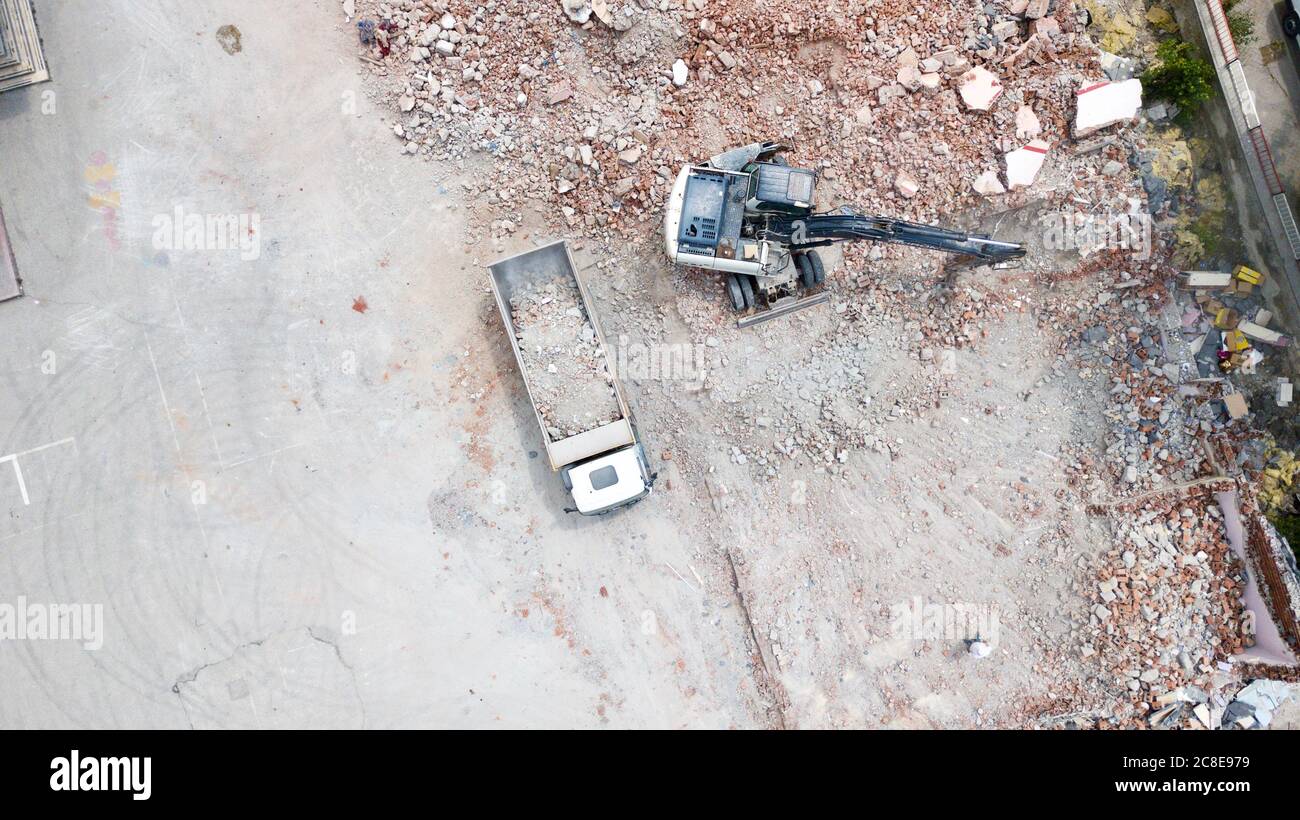 Aerial view of excavator demolishes an old building in city center. Destroyed concrete is loaded on the truck Stock Photo