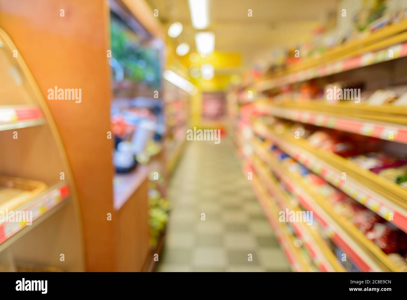 Defocused supermarket aisle with shelves filled with grocery and checkered floor Stock Photo
