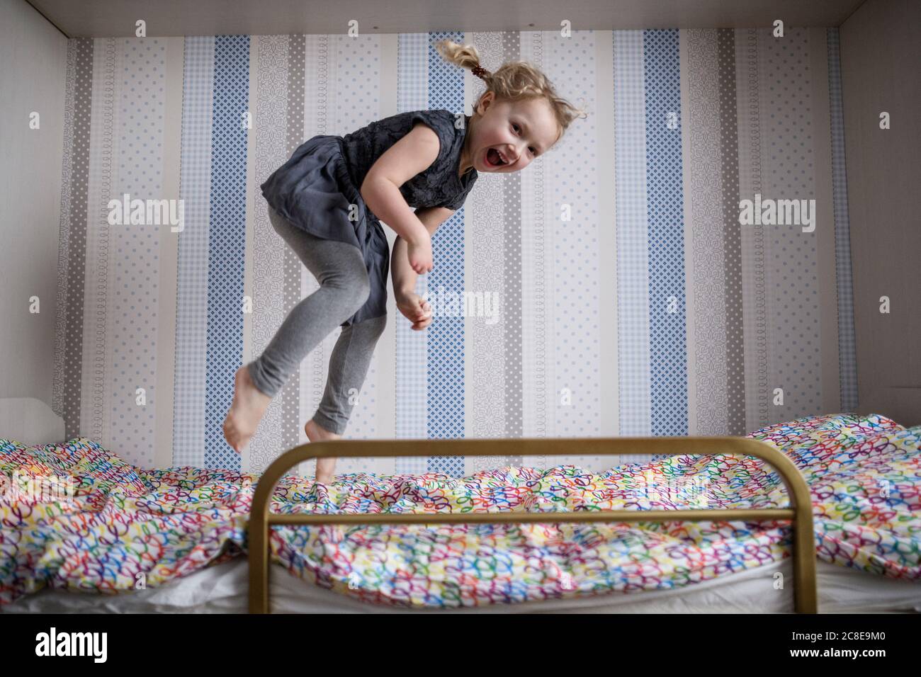 Cheerful girl jumping on bunkbed at home Stock Photo