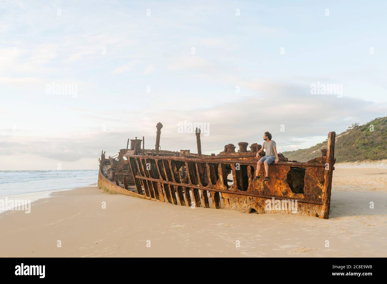 Man sitting on Maheno shipwreck at Fraser Island, Queensland, Australia Stock Photo
