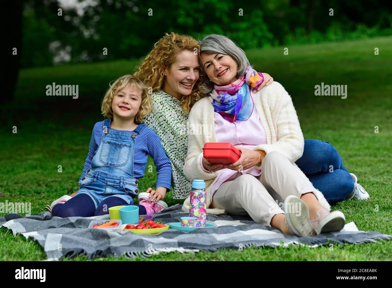 Happy three generation females enjoying picnic at public park Stock Photo