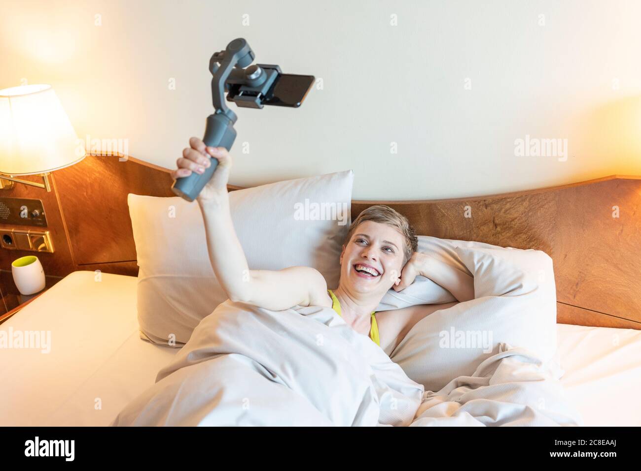 Smiling beautiful woman taking selfie while lying on bed at home Stock Photo