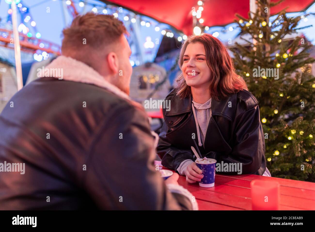 Smiling woman talking with boyfriend while sitting at amusement park Stock Photo