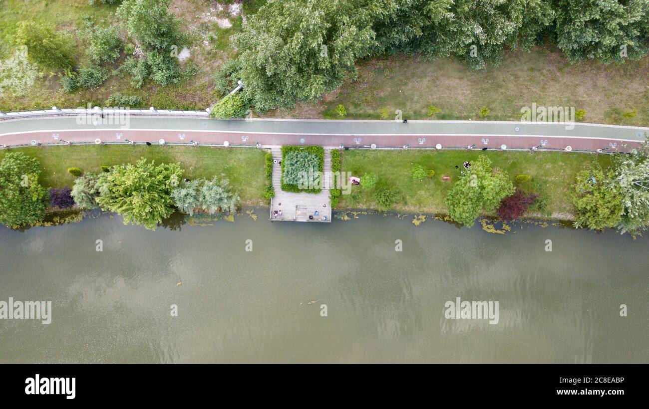 Aerial view of the walking path and bike road near the river and trees. People are walking and cycling also. Stock Photo