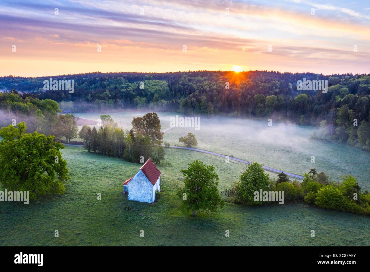 Germany, Bavaria, Egling, Drone view of Kapelle Saint Koloman at foggy springtime sunrise Stock Photo