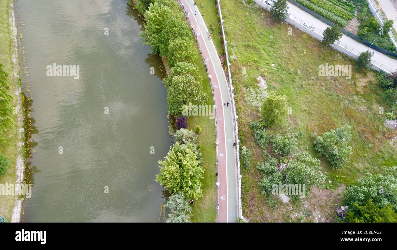 Aerial view of the walking path and bike road near the river and trees. People are walking and cycling also. Stock Photo