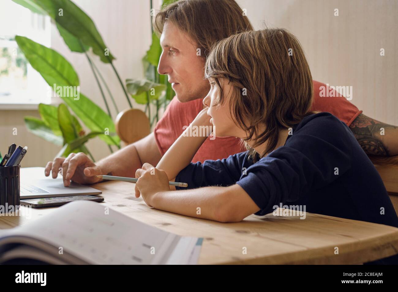 Father and son using laptop while doing homework at home Stock Photo