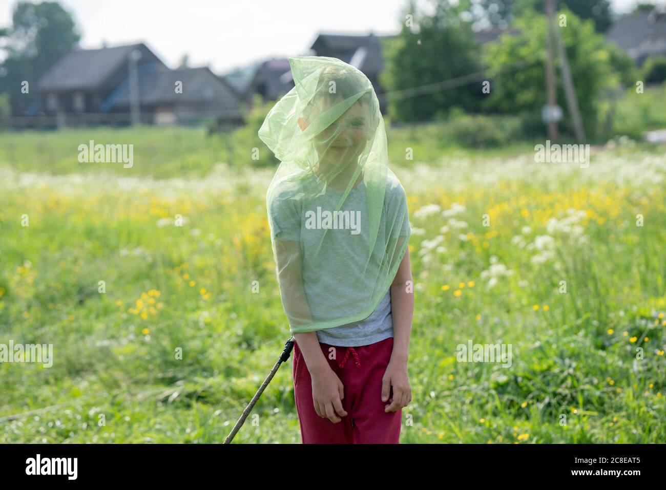 Playful boy wearing butterfly net while standing on grassy land Stock Photo