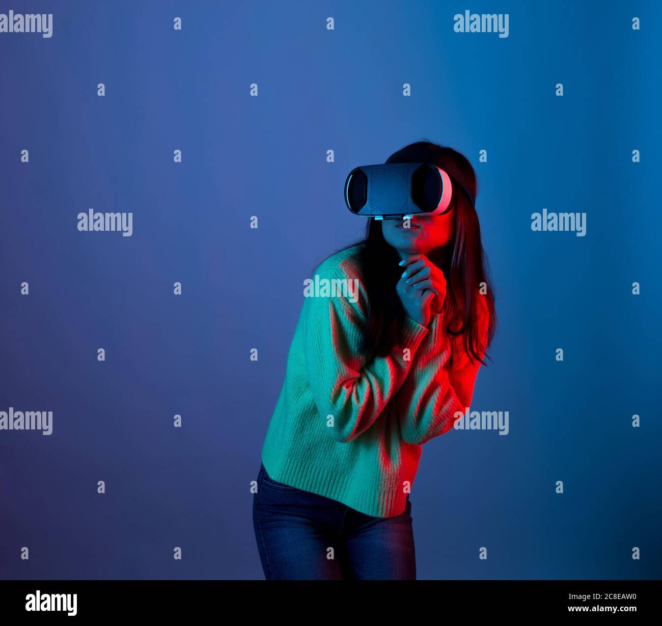 Young woman wearing a vr is making affraid gesture lighted with red and blue Stock Photo