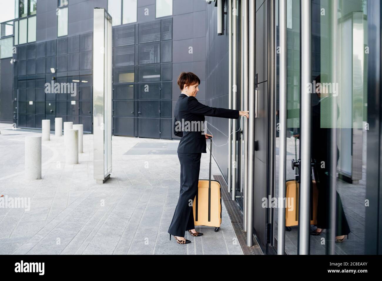 Businesswoman with suitcase entering in modern building Stock Photo