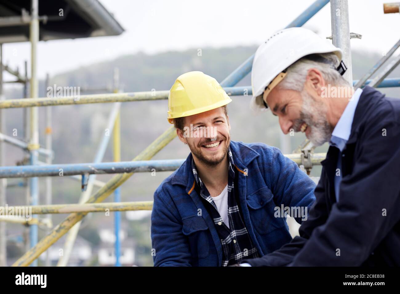 Happy architect and worker on scaffolding on a construction site Stock Photo
