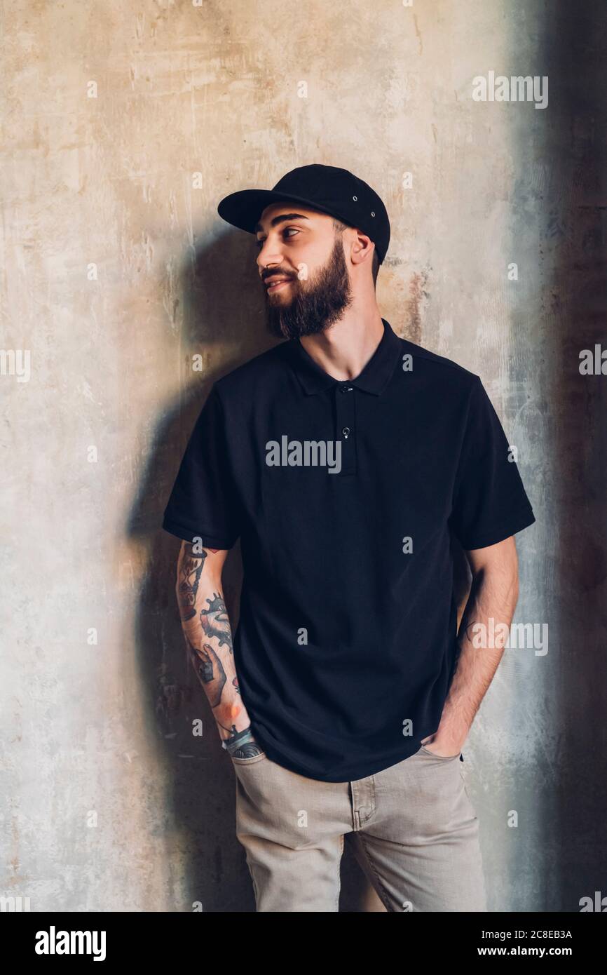 Smiling stylish young man standing at a wall Stock Photo