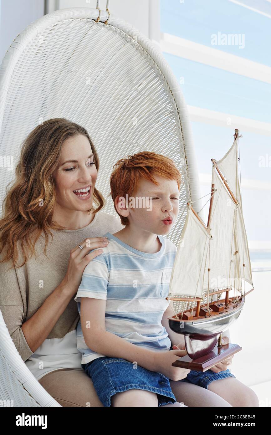 Happy mother and son with model sailing ship in hanging chair Stock Photo