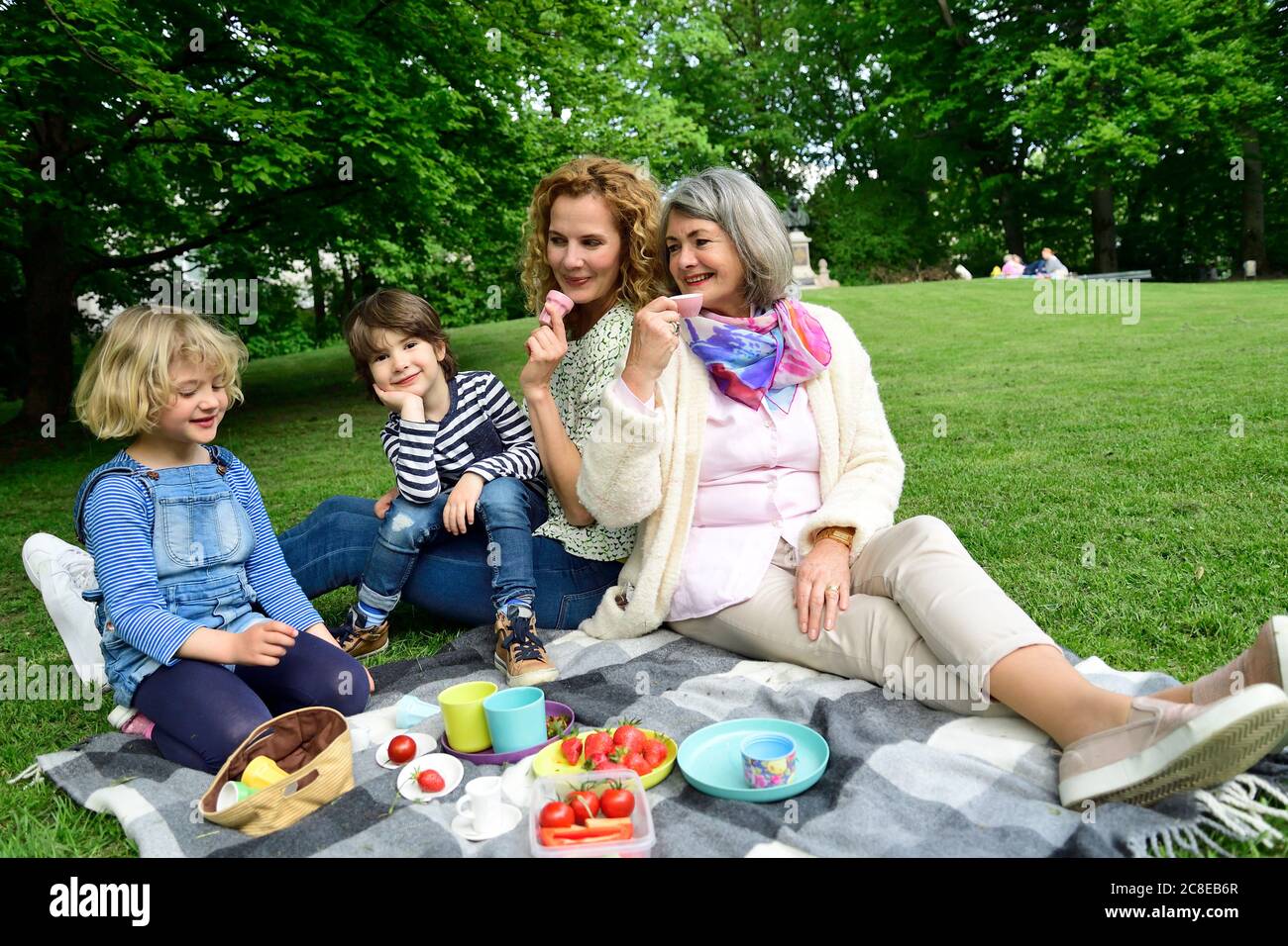 Three generation family enjoying picnic at public park Stock Photo