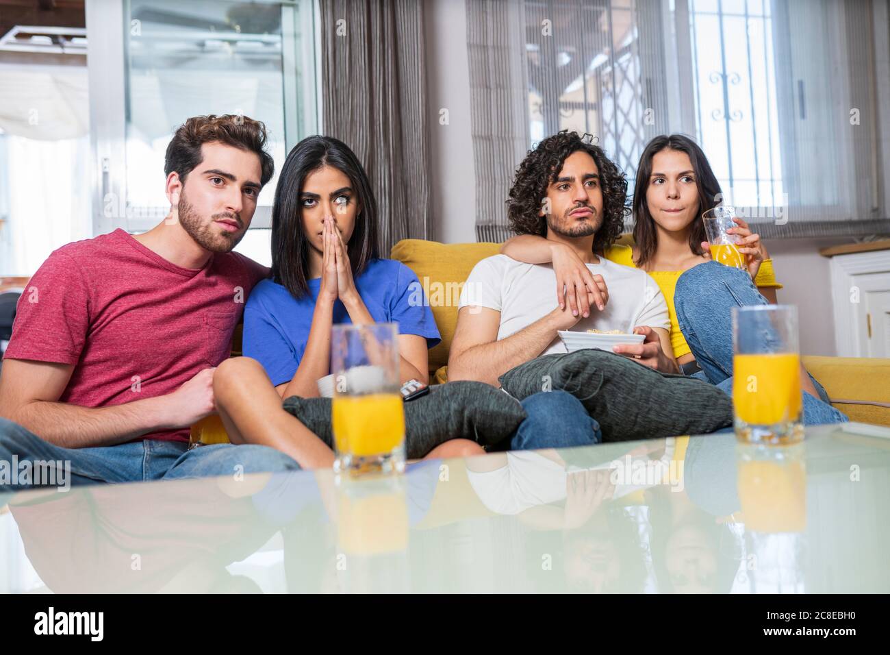 Young multi-ethnic friends in stress watching TV at home Stock Photo