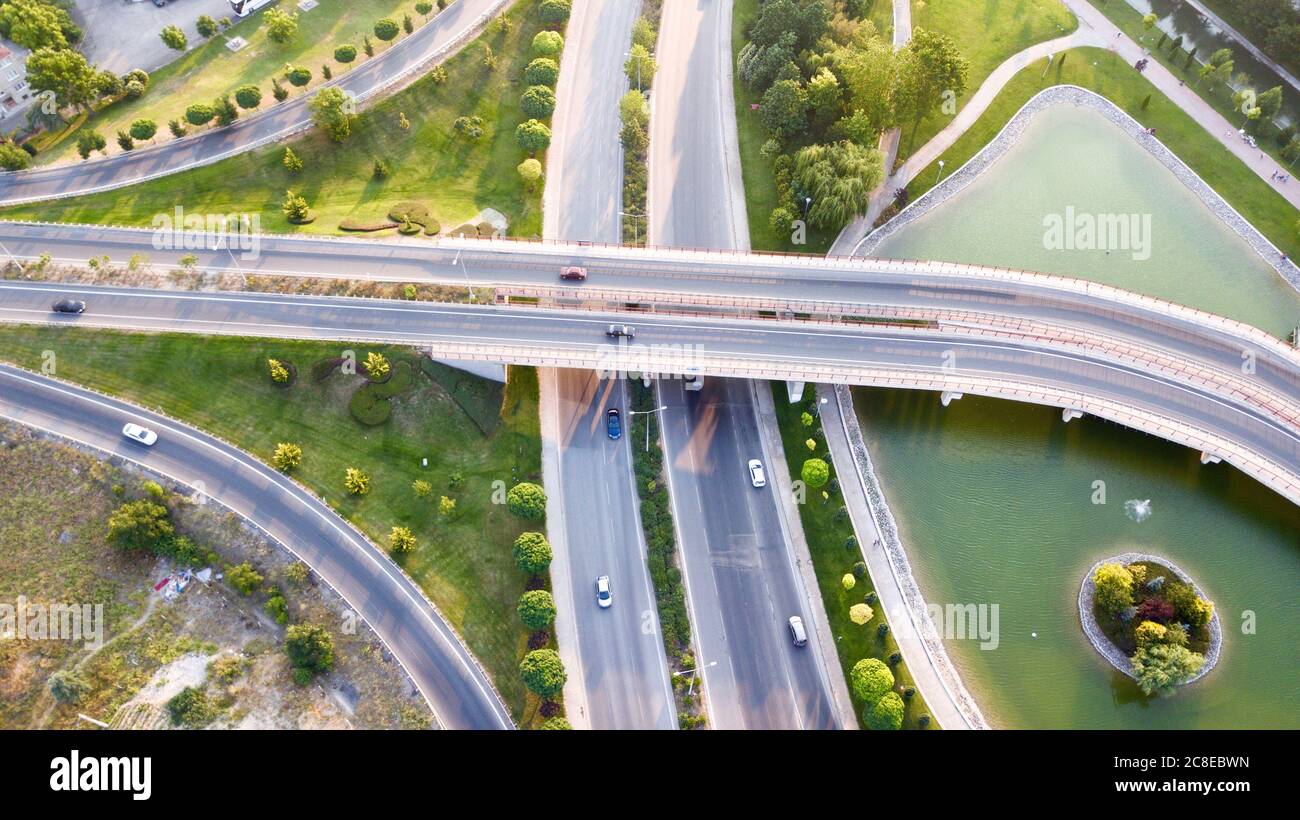 Aerial view of the roundabout on the river. Trees, overpass, buildings and vehicles can be seen. Stock Photo