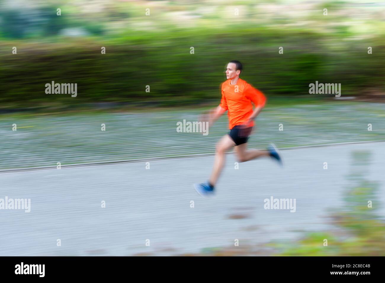 Blurred motion of young man running on footpath Stock Photo