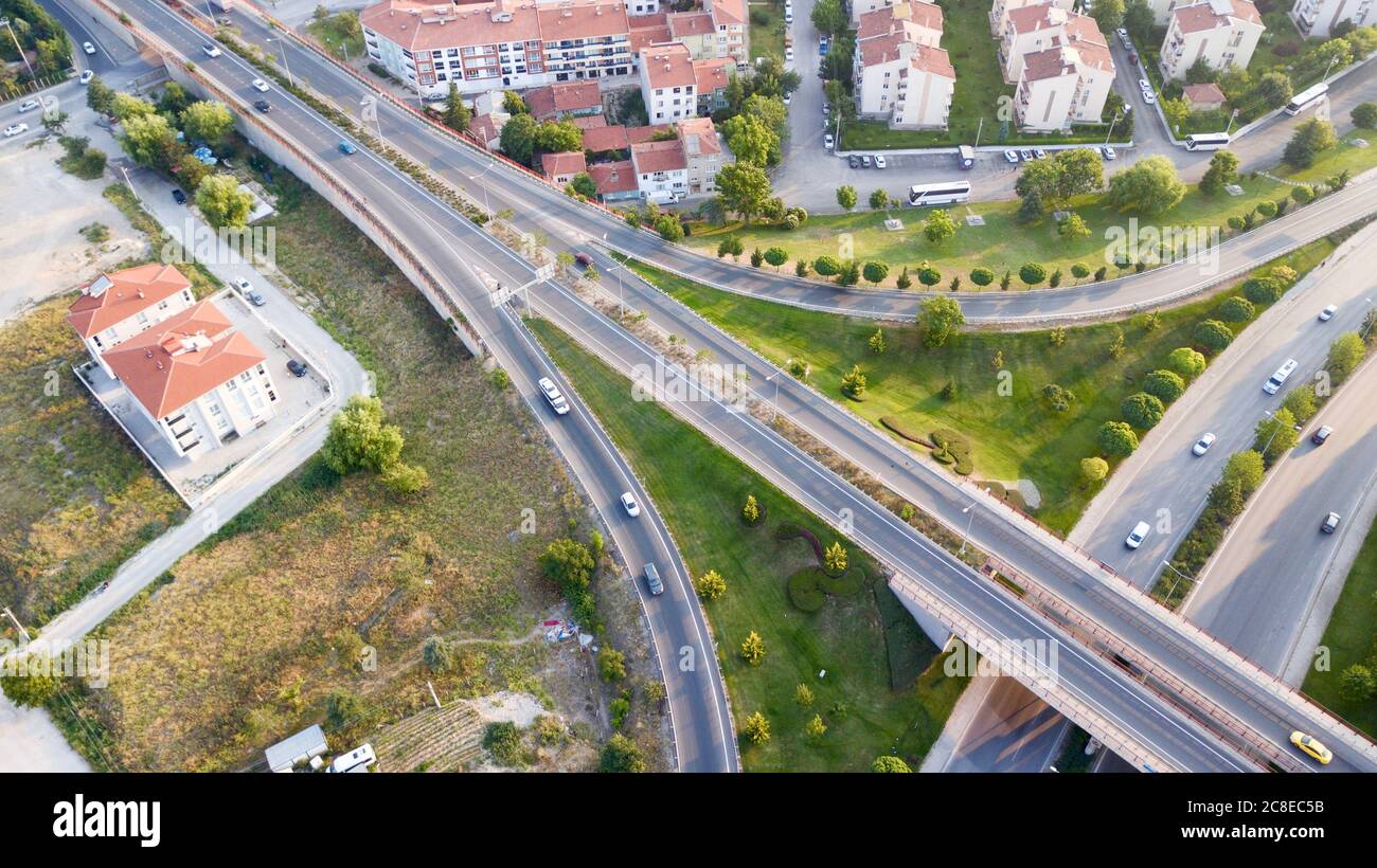 Aerial view of the roundabout on the river. Trees, overpass, buildings and vehicles can be seen. Stock Photo