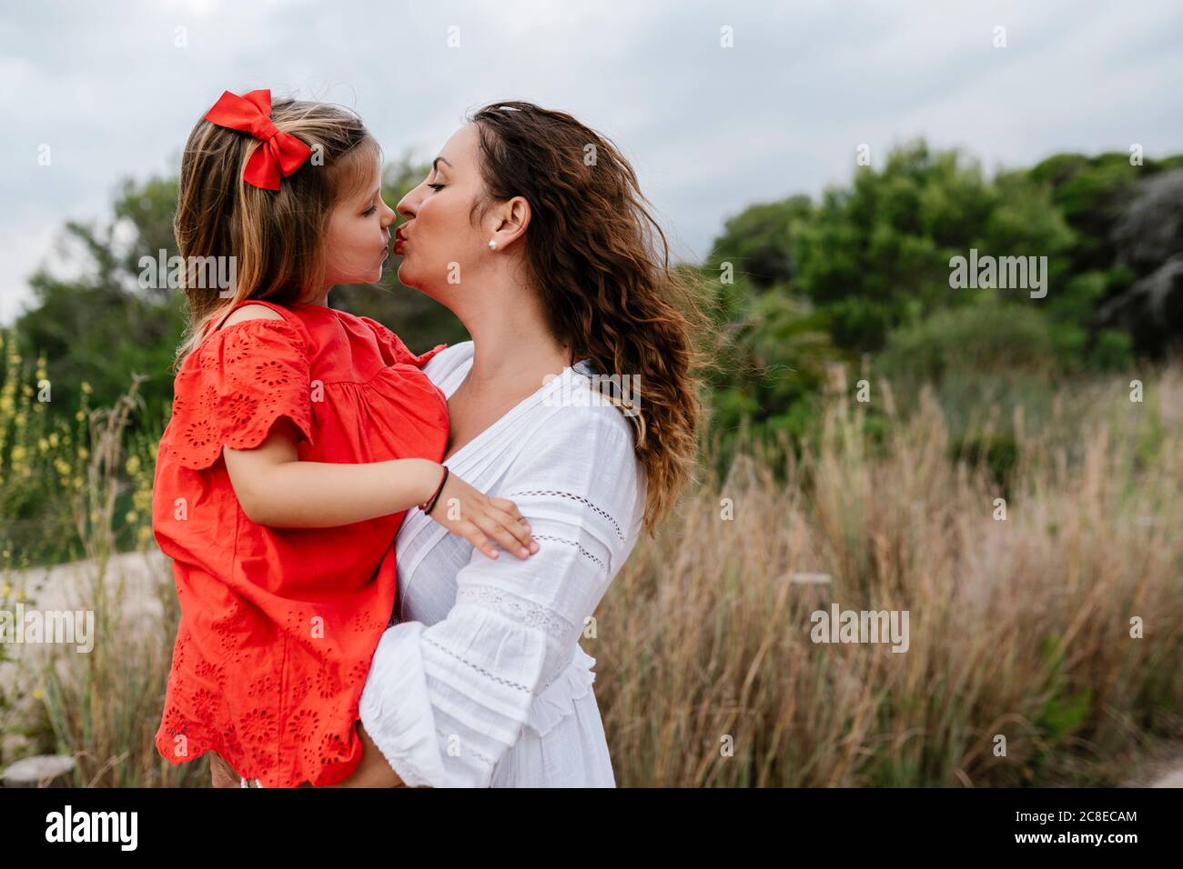 Affectionate mother and daughter kissing at countryside Stock Photo