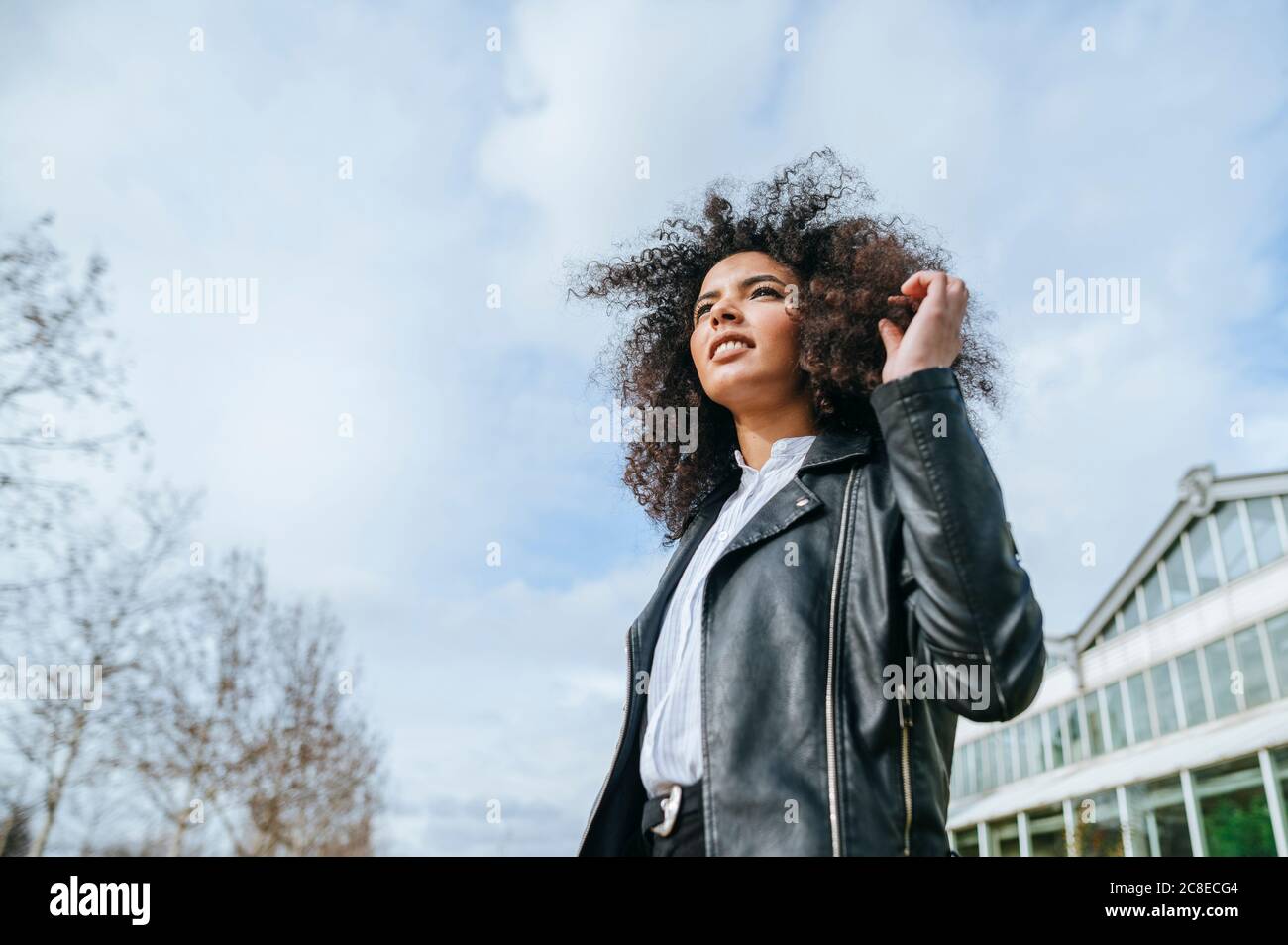 Afro woman looking away against sky Stock Photo