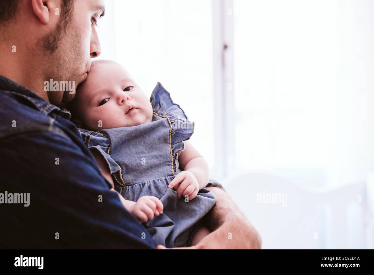 Cute baby girl being carried by father at home Stock Photo Alamy