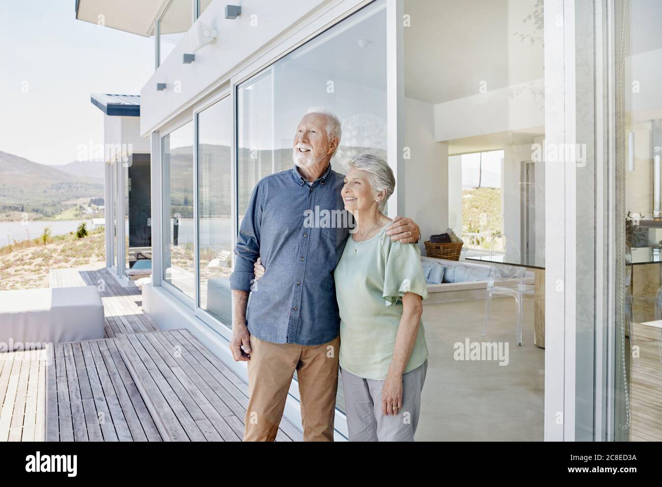 Happy senior couple standing at luxury beach house Stock Photo