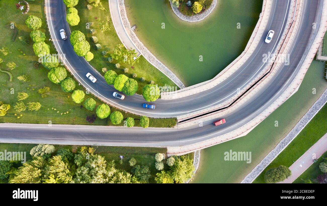 Aerial view of the roundabout on the river. Trees, overpass, buildings and vehicles can be seen. Stock Photo