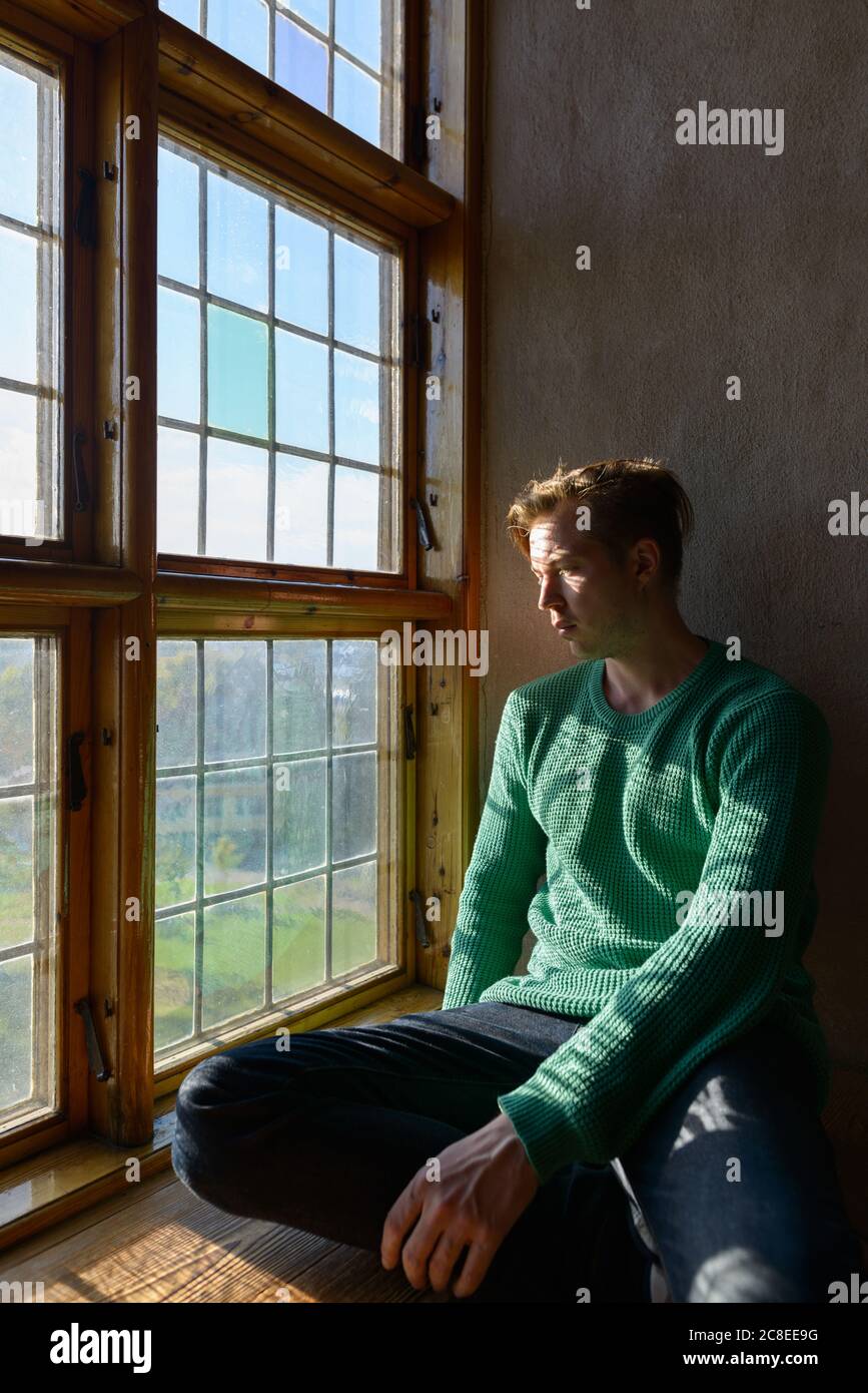 Free Stock Photo of Young Man sitting near window