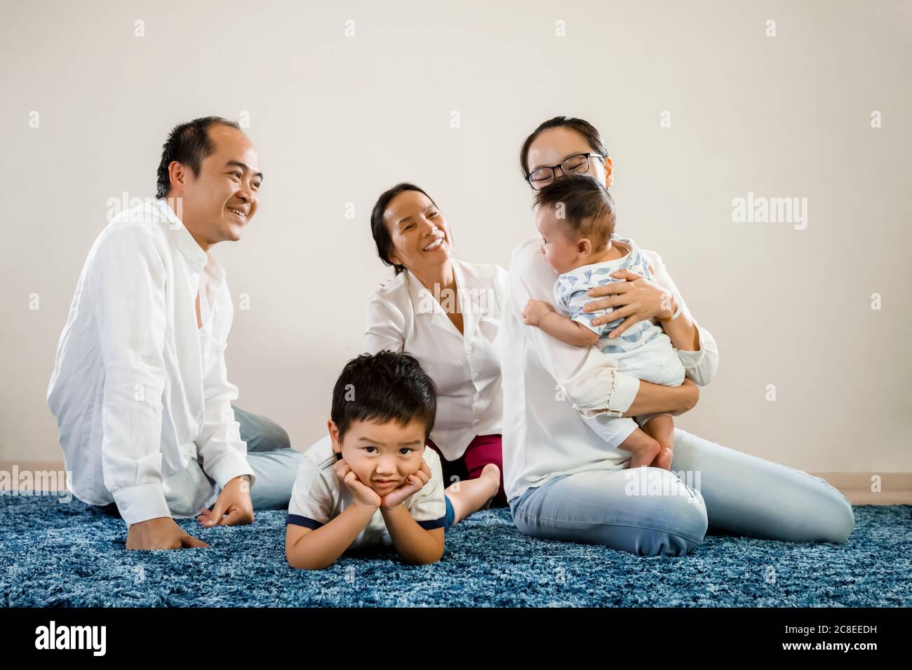 New sibling asian baby brother gets all the attention, jealous older sibling foreground with parents playing with new born younger child. asian family Stock Photo