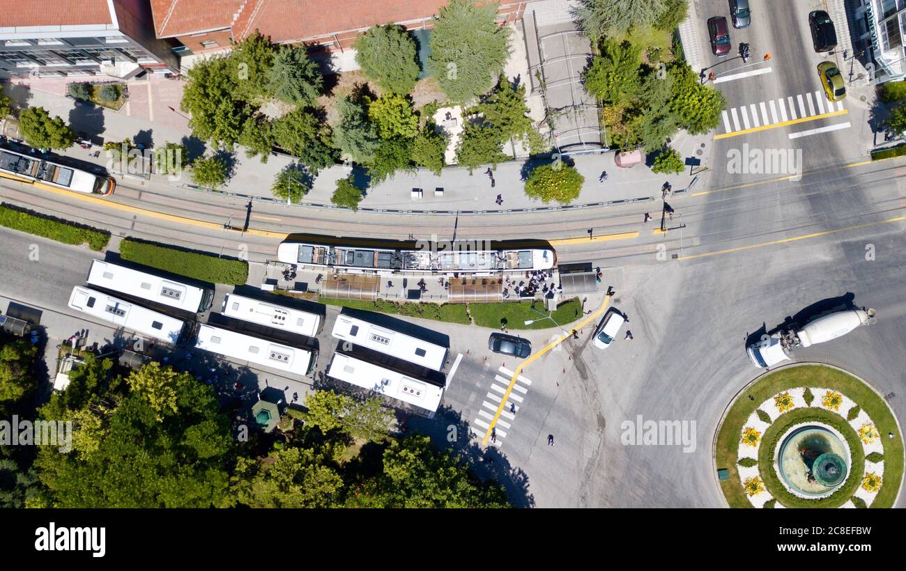 Aerial view of tram station at the city center. City buses are waiting in red light and people are crossing the pedestrian path. Stock Photo