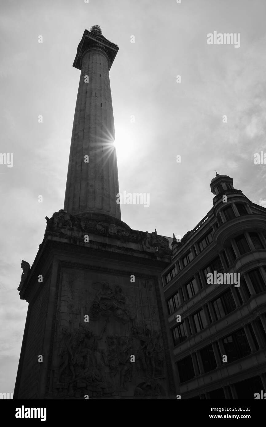 Silhouette of the Monument to the Great Fire of London in 1666 with starburst Sun in black and white shot. Stock Photo