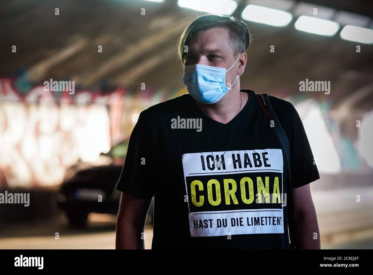 Duisburg, Germany, July 23rd, 2020: Man with a face mask is wearing a t-shirt that says 'I have Corona, do you have limes?'. This does not mean the virus Covid-19, but the Mexican beer brand Corona, which is drunk with lime in the bottle neck. Stock Photo