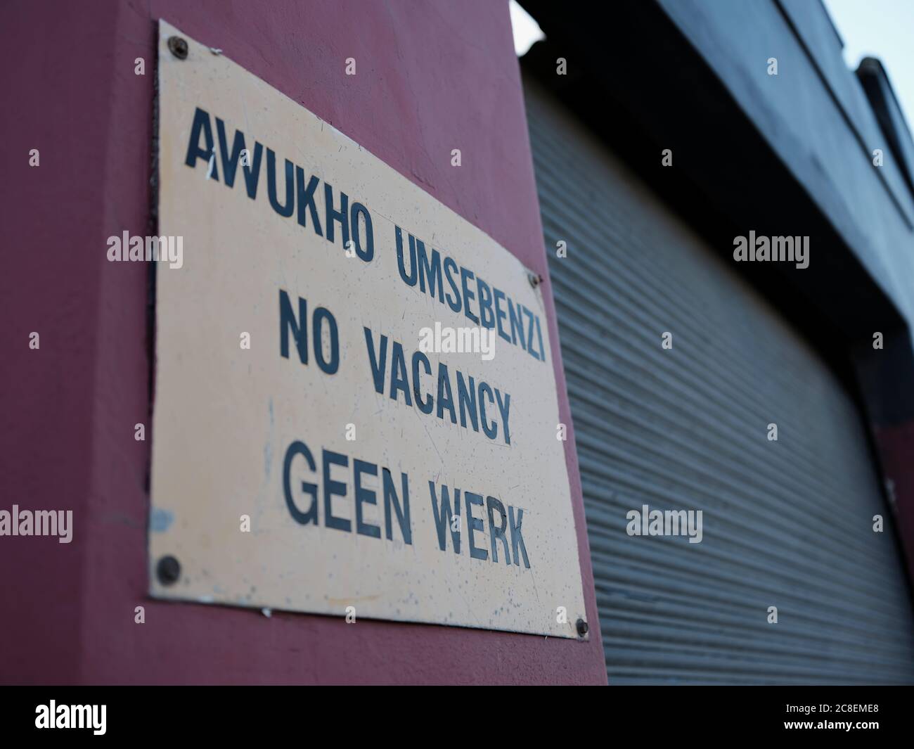 No vacancy sign mounted on an outside wall of an industrial building in Cape Town, South Africa. The sign is in Zulu, English and Afrikaans. Stock Photo