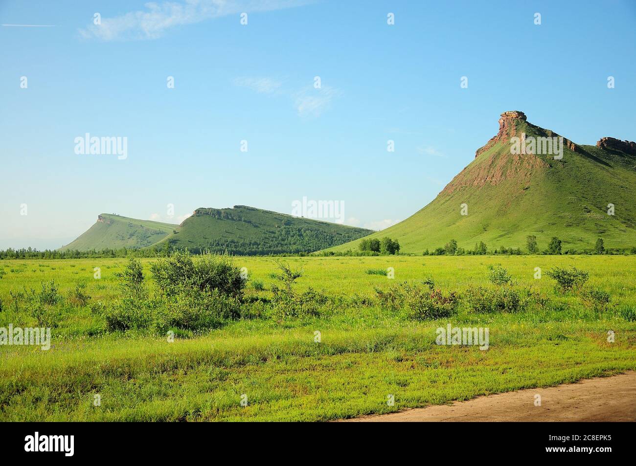 High hills overgrown with grass stand in a row with bizarre buildings