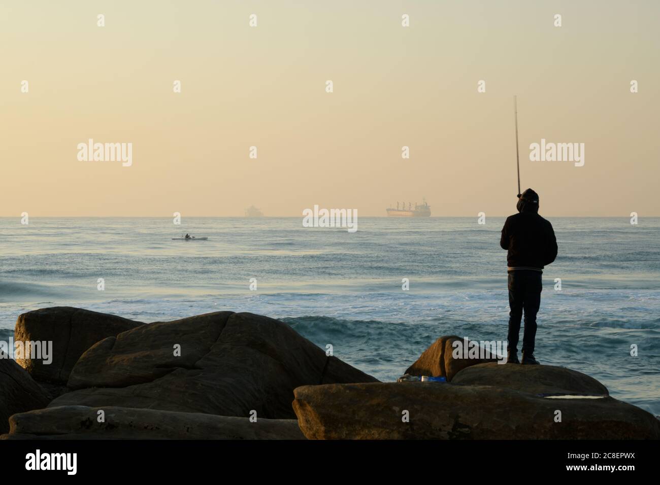 Landscape, Durban, South Africa, silhouette, fisherman standing on rock, Umhlanga Rocks beach, waterfront, KwaZulu-Natal, sunrise, fishing, background Stock Photo