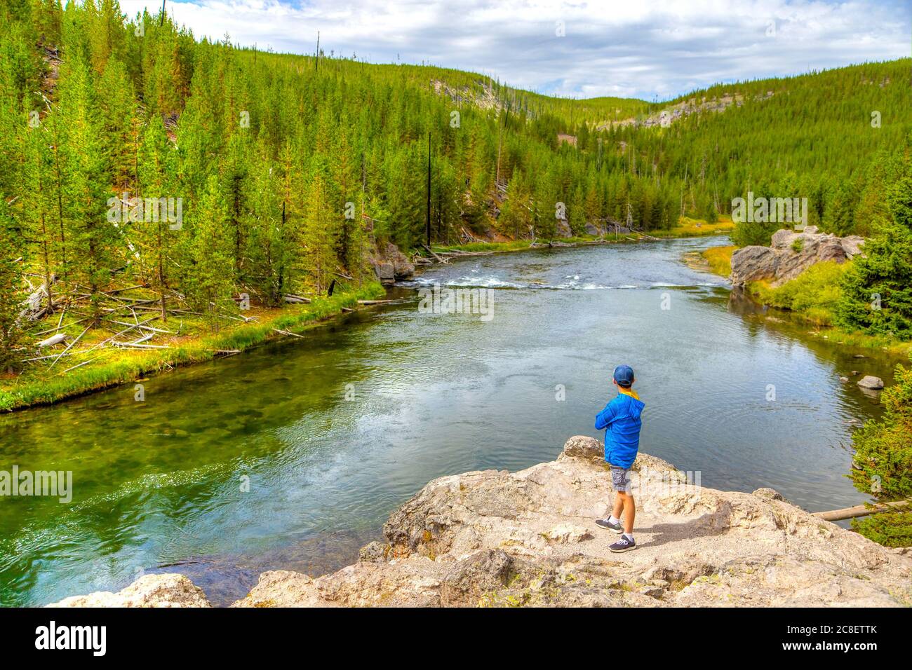 A young visitor looking toward Firehole River in Yellowstone National Park, Wyoming, USA. The river flows through several significant geyser basins in Stock Photo
