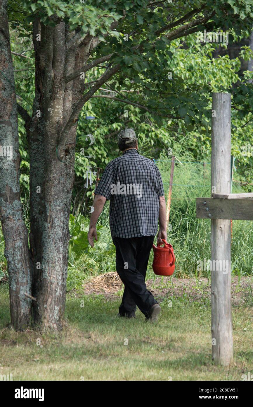 man walking with garden watering container Stock Photo
