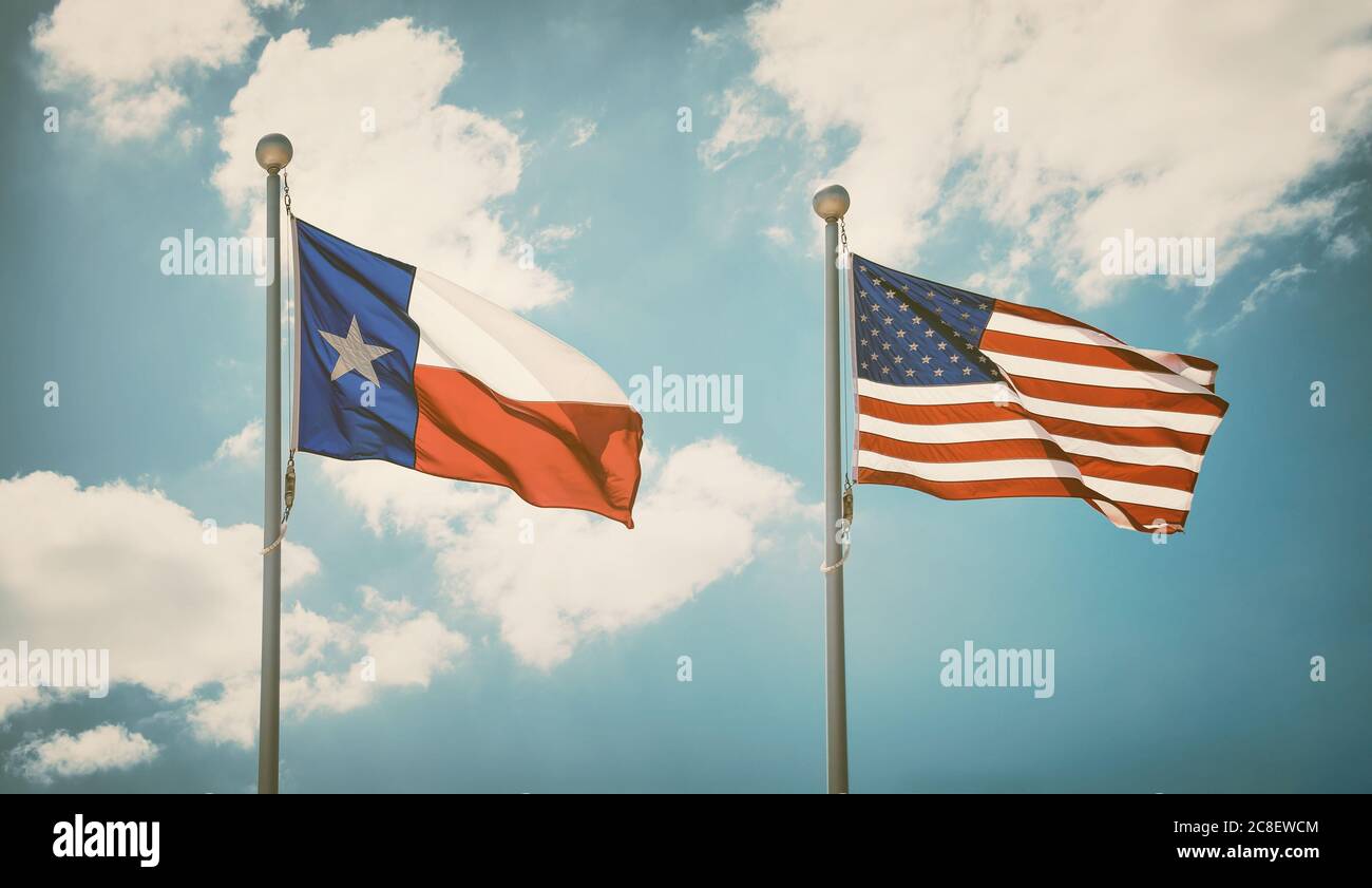 The state flag of Texas and American flag waving in the wind on flagpoles. Blue sky background and white clouds. Vintage filter effects. Stock Photo
