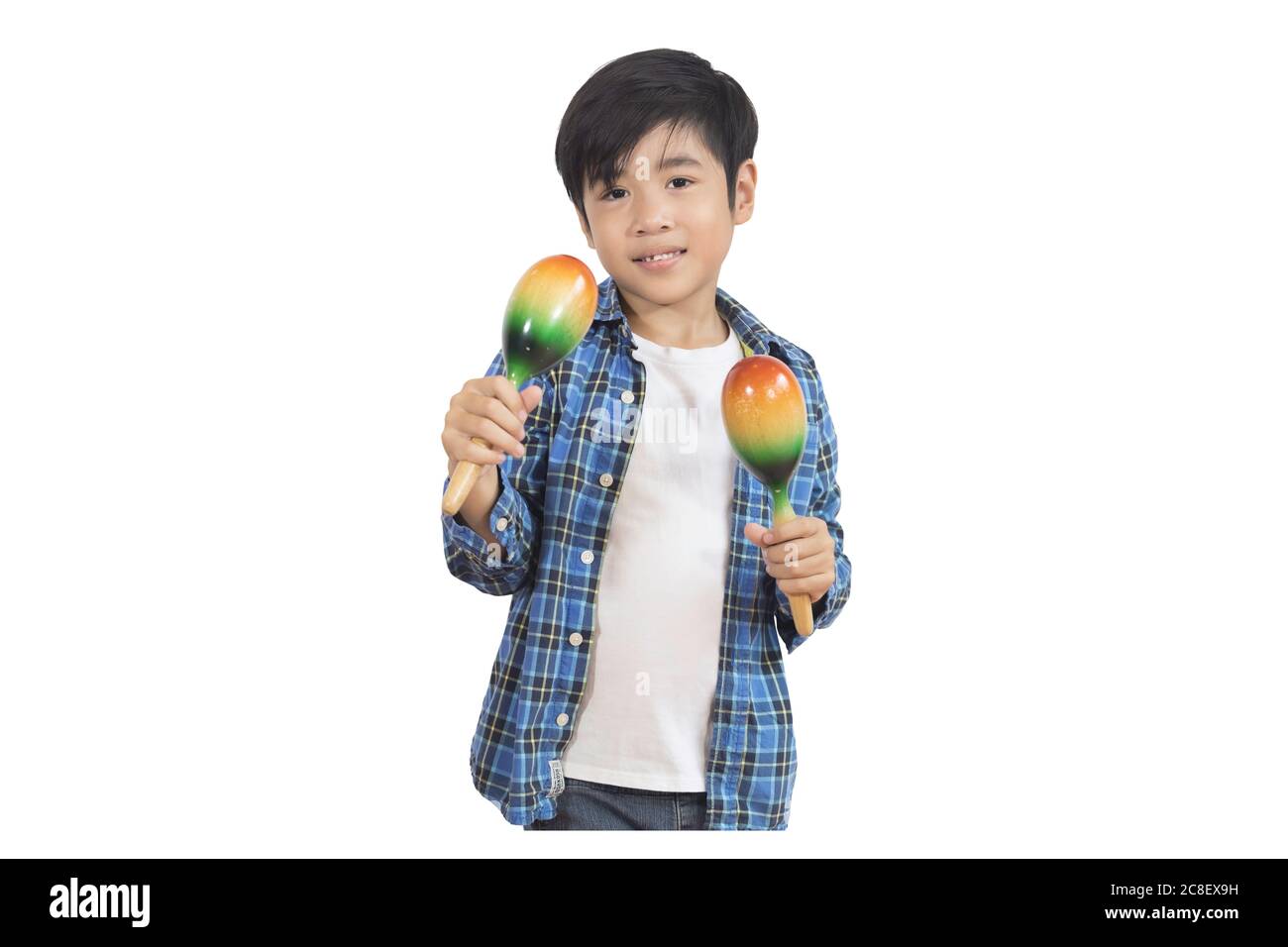Portrait of a cute Asian elementary school boy wearing a jeans and a plaid shirt with maracus, a musical instrument that shakes to make sounds. An iso Stock Photo