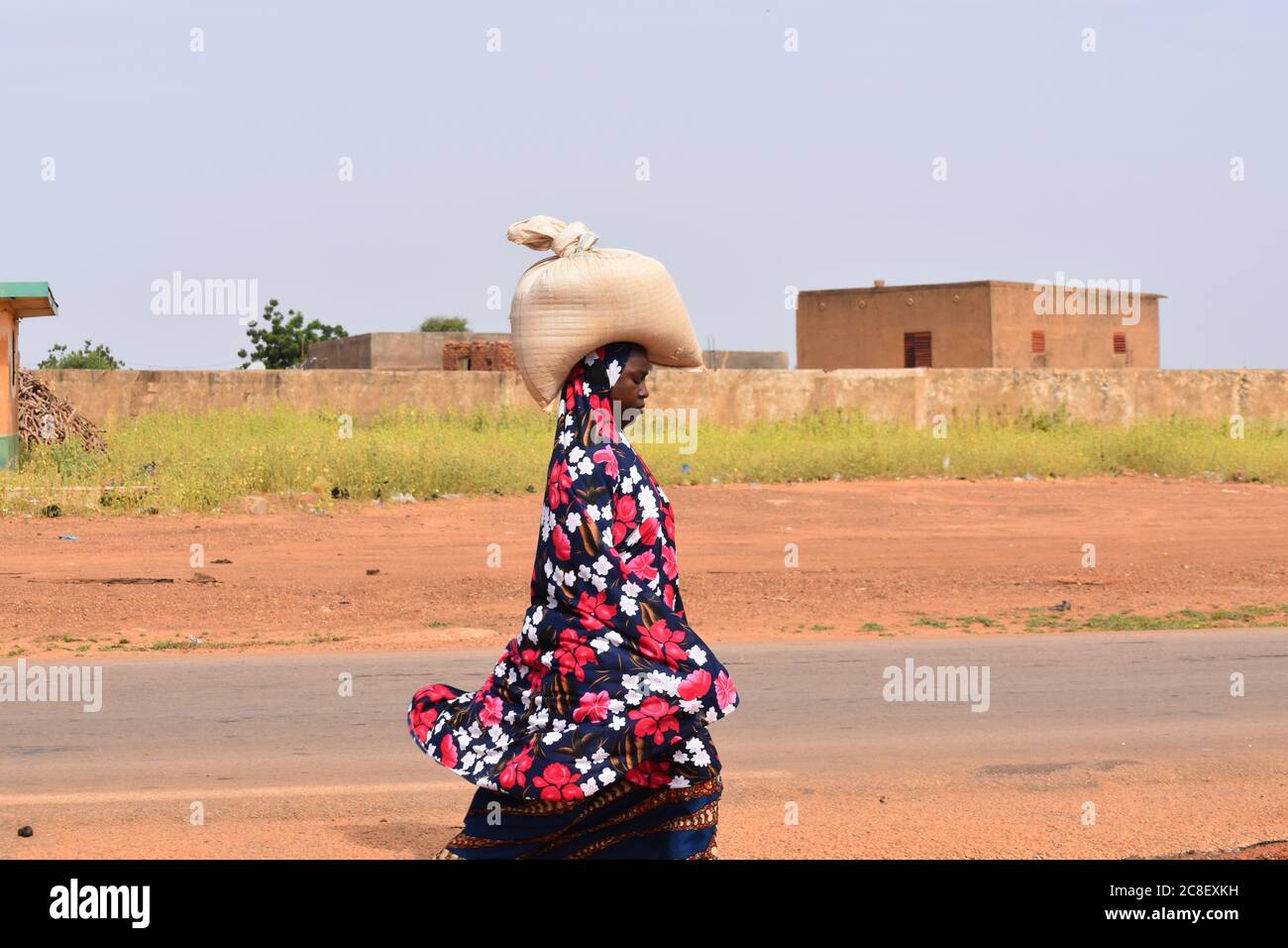 An African woman carrying a full sack on her head Stock Photo
