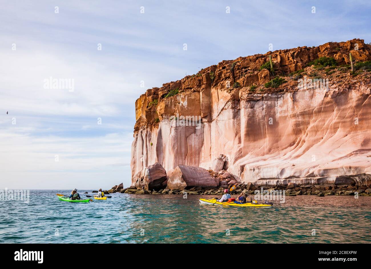 A guided sea kayaking tour offshore below towering sandstone cliffs on Isla Espirito Santo, Gulf of California, BCS, Mexico. Stock Photo