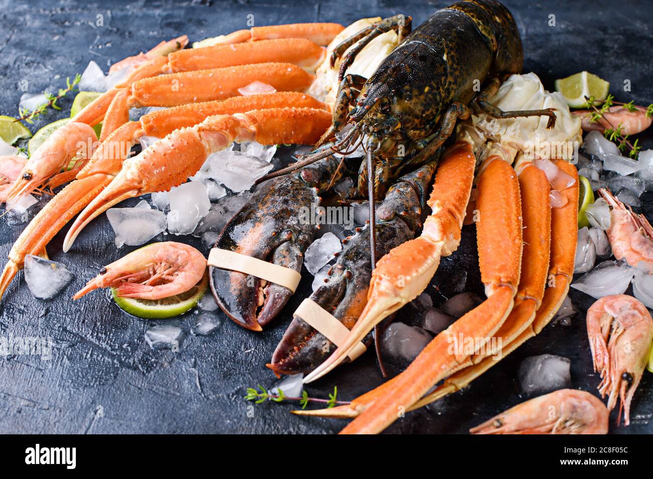 Delicious fresh fish and seafood on dark vintage background. Fish, clams and shrimps with aromatic herbs, spices and vegetables - healthy food, diet o Stock Photo